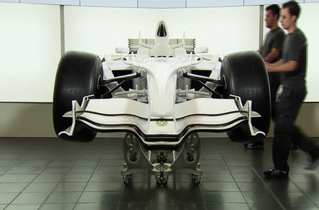 Sauber F1 Team mechanics slice a Formula One race car into two pieces.